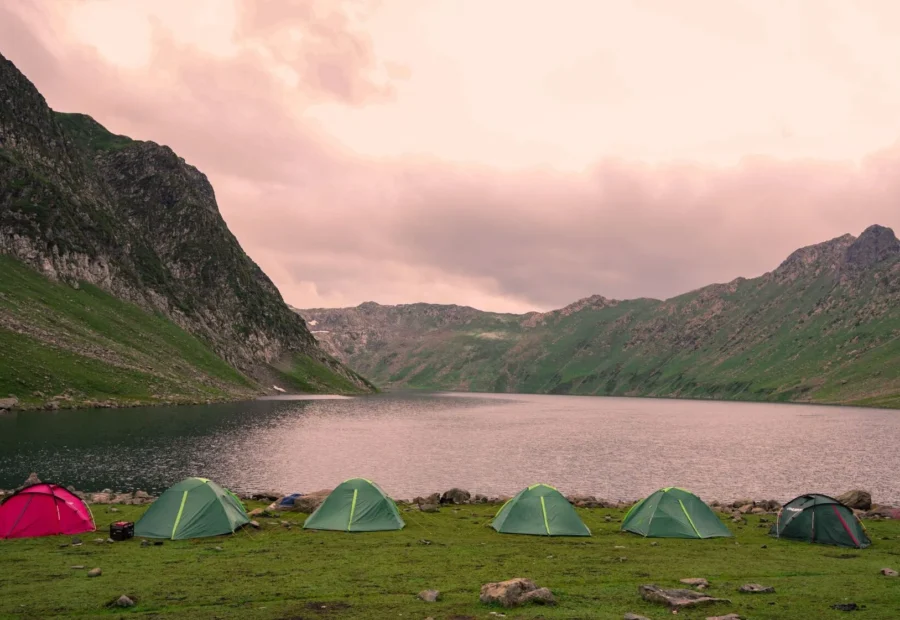 Area tempat destinasi camping seru dengan tenda berlatar pemandangan pegunungan dan alam asri