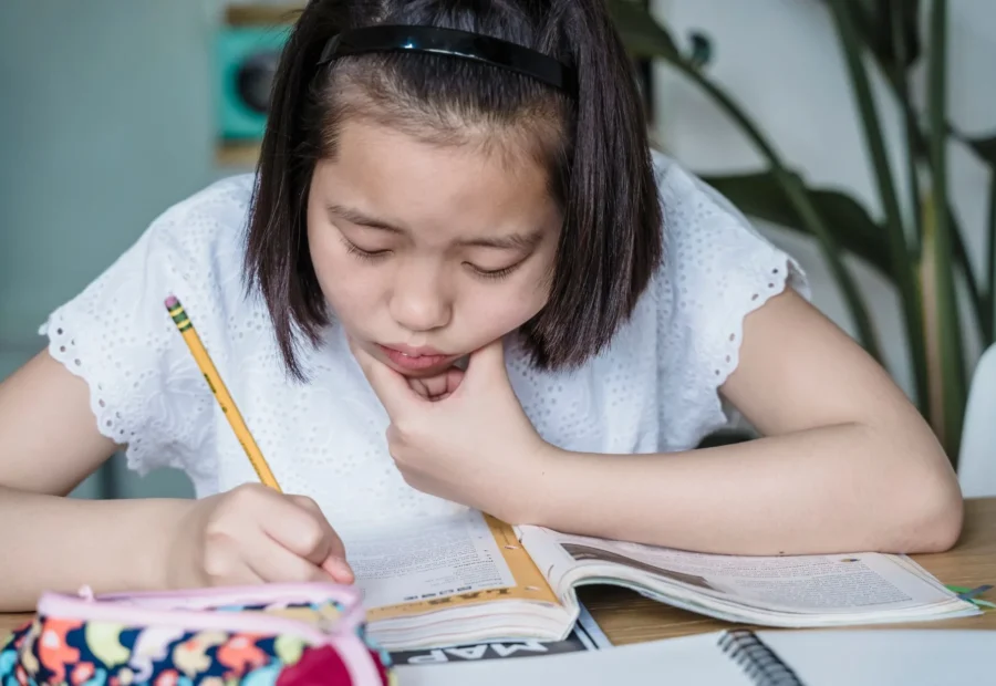Anak sedang belajar dengan tekun di meja belajar yang rapi sebagai tips mengatasi anak susah fokus belajar